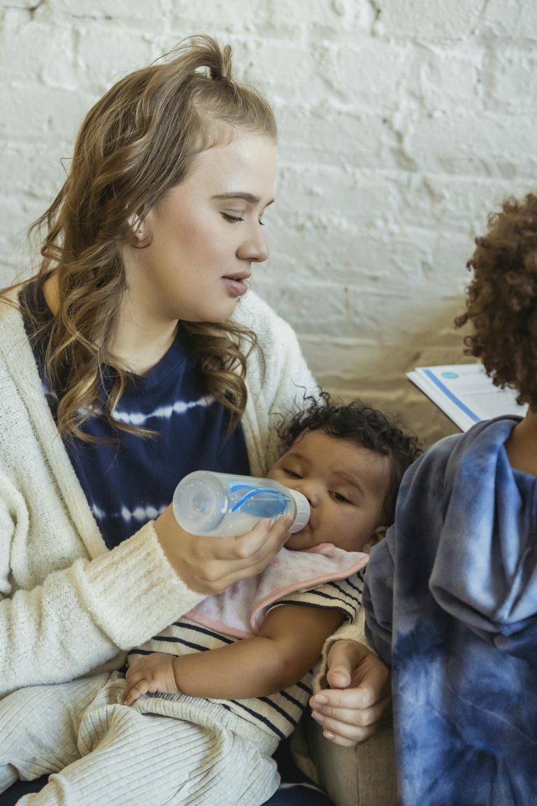 A tender moment of a mother feeding her baby with a bottle indoors.