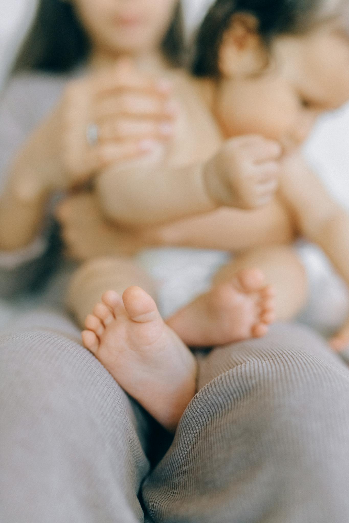 Tender close-up of a baby’s feet with a parent in the background, conveying warmth.
